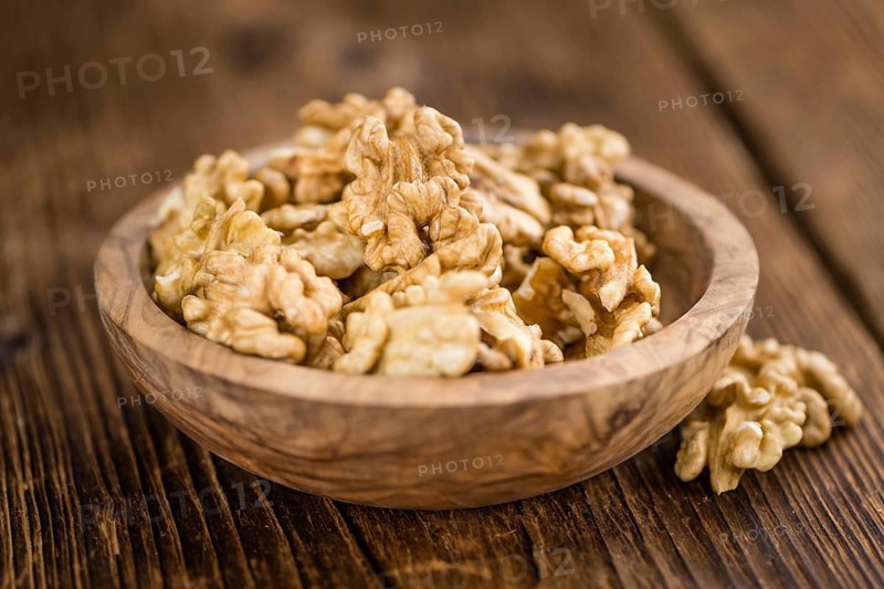 Cracked Walnuts as high detailed close-up shot on a vintage wooden table (selective focus)