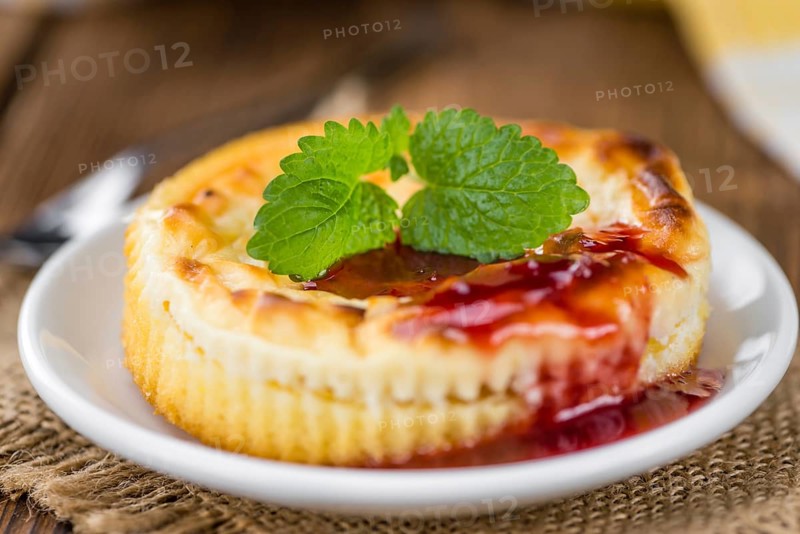 Mini Cheesecake (with Sauce) as high detailed close-up shot on a vintage wooden table (selective focus)