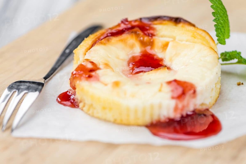 Mini Cheesecake (with Sauce) as high detailed close-up shot on a vintage wooden table (selective focus)