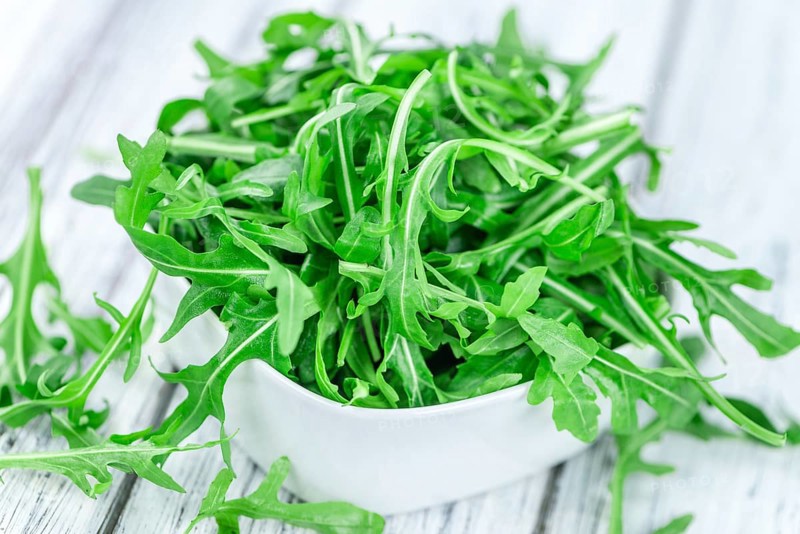 Wooden table with fresh Arugula as detailed close-up shot (selective focus)