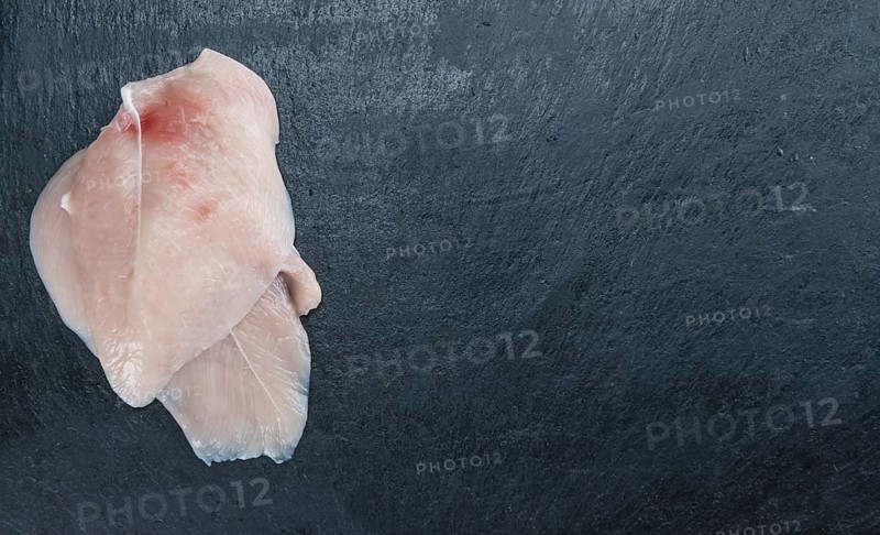Raw Chicken Cutlet on a slate slab (detailed close-up shot)