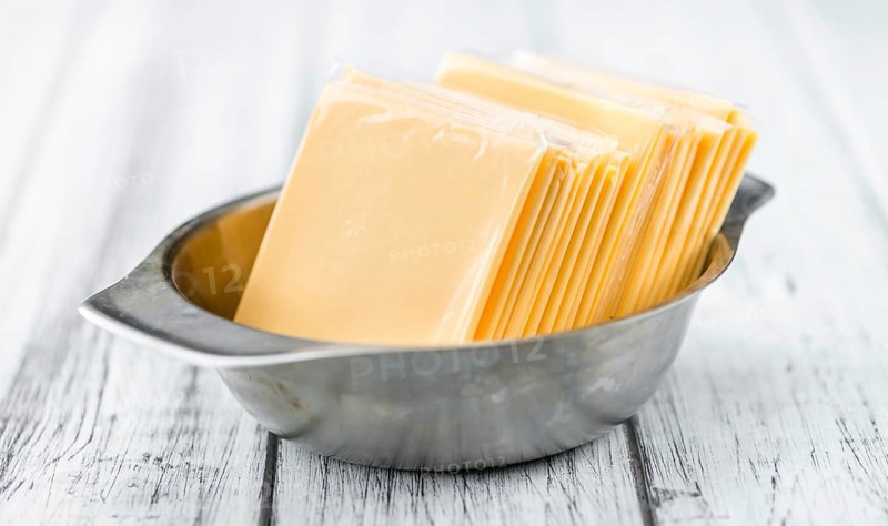 Cheese (sliced) on an old wooden table as detailed close-up shot (selective focus)