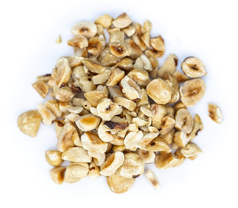 Freshly chopped Hazelnuts as detailed close up shot isolated on white background (selective focus)