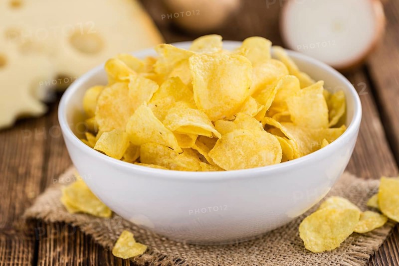 Homemade Cheese and Onion Potato Chips on vintage background (selective focus, close-up shot)