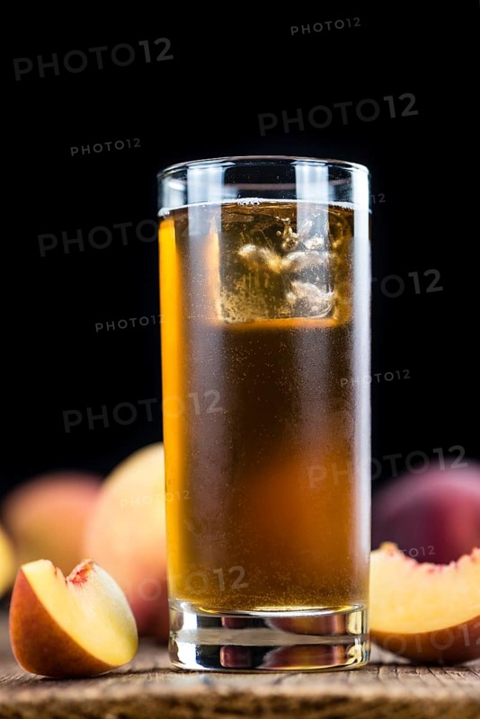 Peach ice tea (selective focus) on an old wooden table (close-up shot)