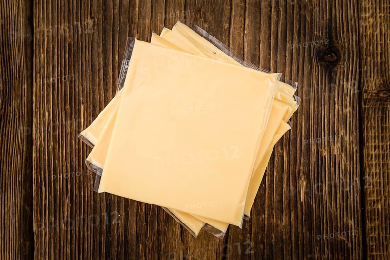 Cheese (sliced) on an old wooden table as detailed close-up shot (selective focus)
