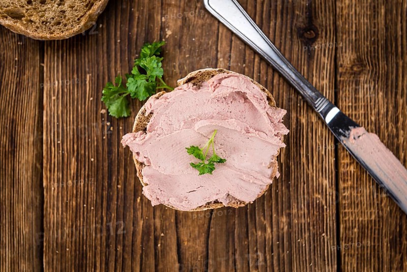 Roll with Liverwurst (German cuisine) on an old wooden table as detailed close-up shot (selective focus)