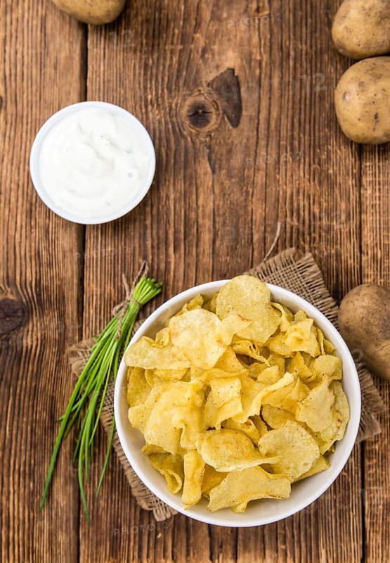 Fresh made Potato Chips with Sour Cream taste on a vintage background (close-up shot)