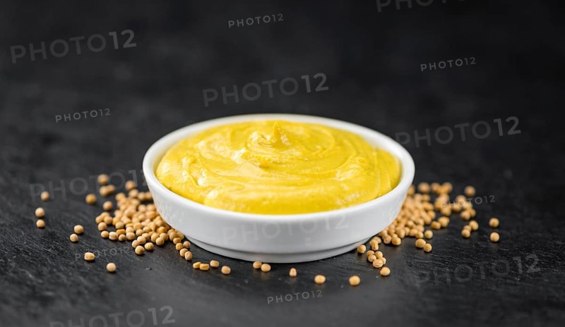 Fresh made Mustard on a vintage background (close-up shot)