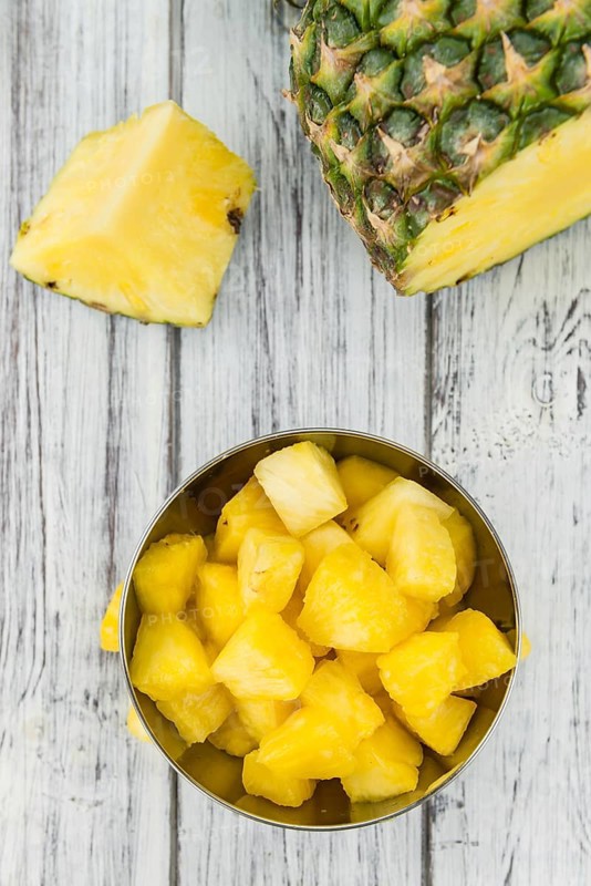 Sliced Pineapple on an old wooden table as detailed close-up shot, selective focus