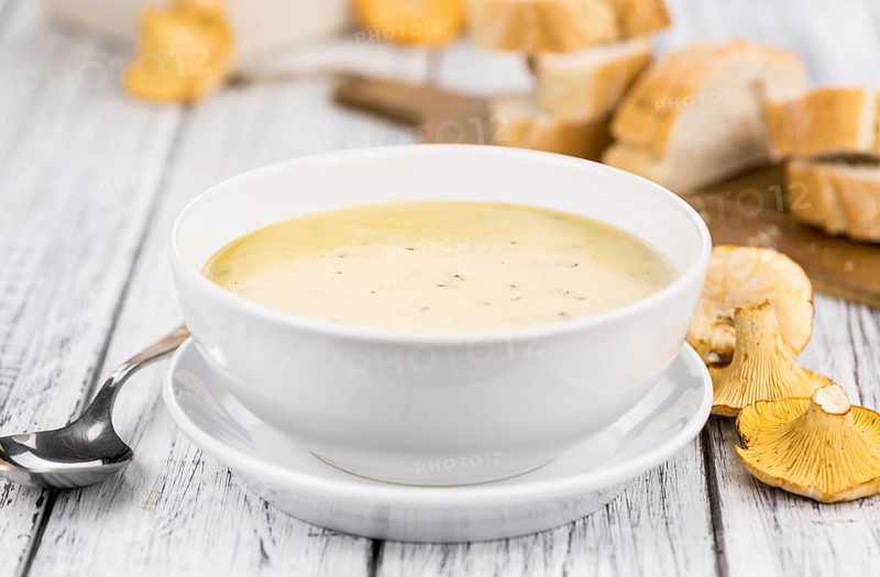 Chanterelle Soup as high detailed close-up shot on a vintage wooden table, selective focus