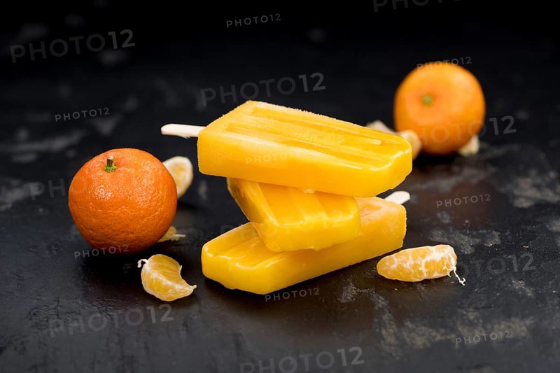 Portion of fresh homemade Tangerine Popsicles (close-up shot, selective focus) on a vintage background