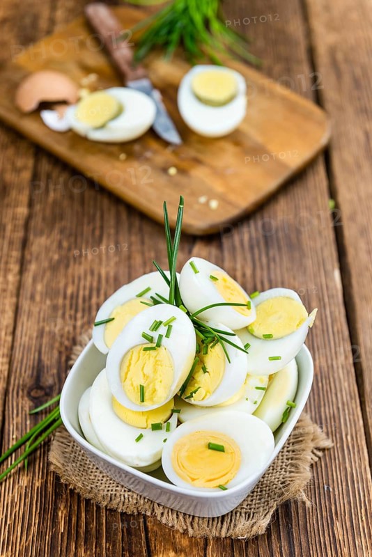 Halved Eggs on wooden background (close-up shot, selective focus)
