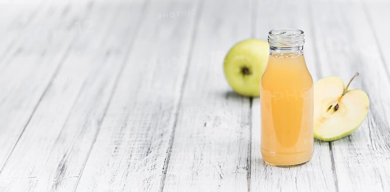 Homemade Apple Juice on an wooden table (selective focus) as detailed close-up shot