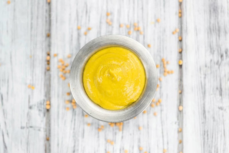 Portion of homemade Mustard on wooden background (selective focus, close-up shot)