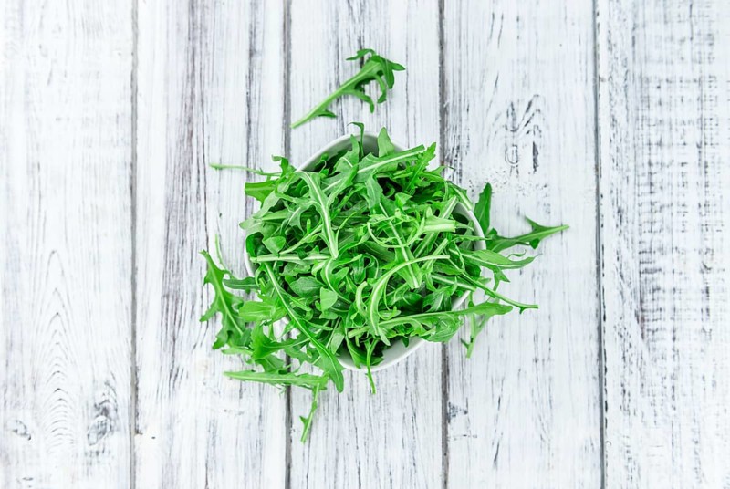 Fresh Arugula on an old wooden table as detailed close-up shot