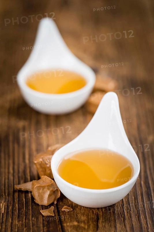 Caramel Syrup as high detailed close-up shot on a vintage wooden table (selective focus)