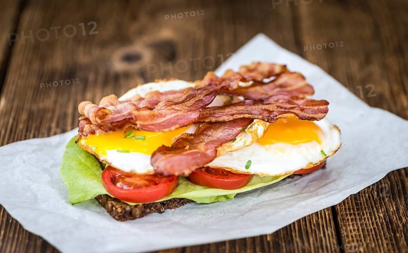 Wooden Table with Bacon and Eggs (selective focus, close-up shot)