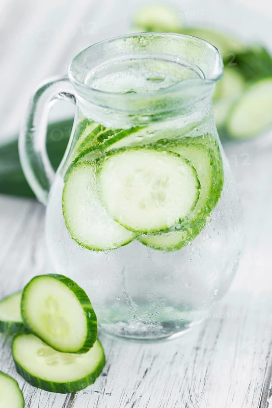 Fresh made Cucumber Water as high detailed close-up shot on a vintage wooden table, selective focus