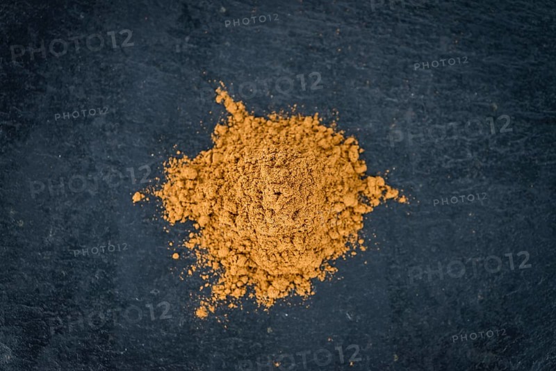 Portion of Cinnamon Powder on a rustic slate slab (selective focus, close-up shot)