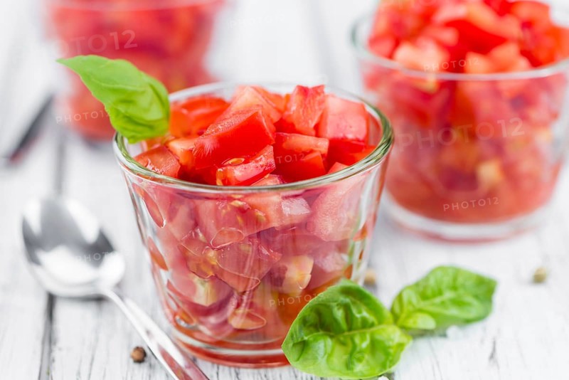 Tomatoes (diced) as high detailed close-up shot on a vintage wooden table (selective focus)