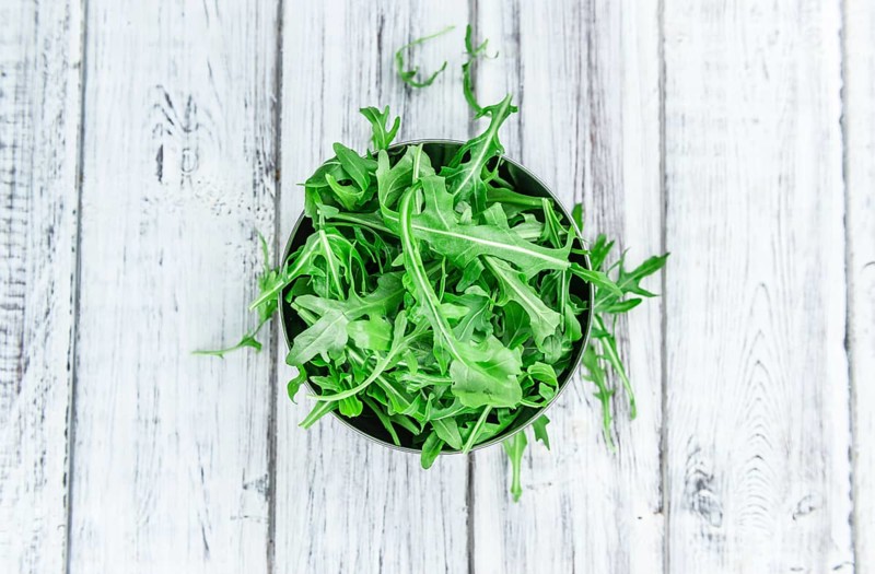 Fresh Arugula (selective focus) as detailed close-up shot on vintage background