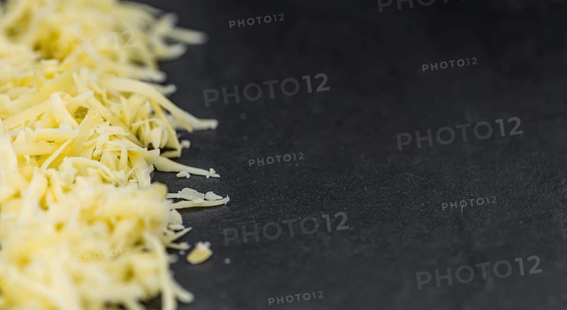 Homemade Grated Cheese (close-up shot) on a vintage slate slab