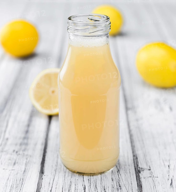 Homemade Lemon Juice on an wooden table (selective focus) as detailed close-up shot