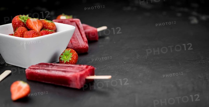 Slate slab with homemade Strawberry Popsicles (selective focus, close-up shot)