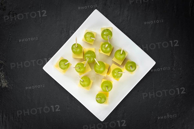 Cheese blocks with grapes as close-up shot on a vintage looking slate slab (selective focus, partyfood)