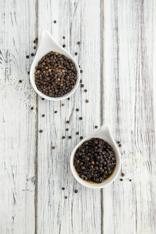Black Peppercorns preserved on wooden background, selective focus, close-up shot