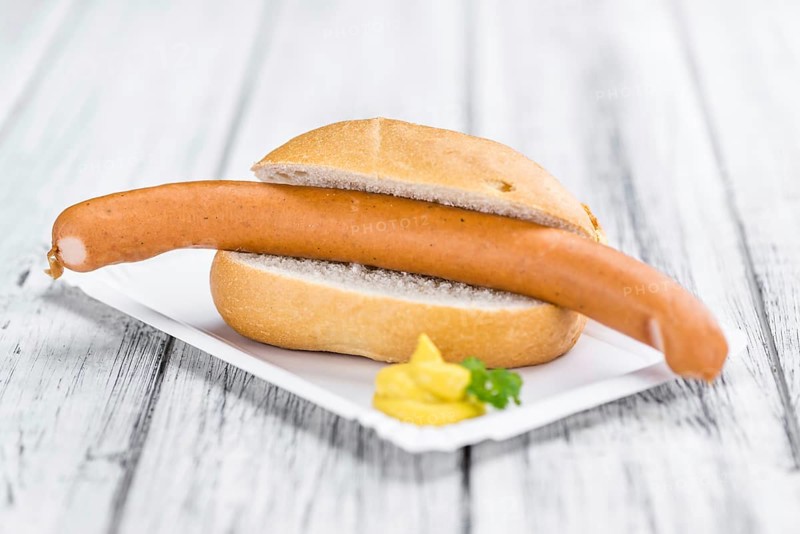 Sausages (Frankfurter) on rustic wooden background (close-up shot)