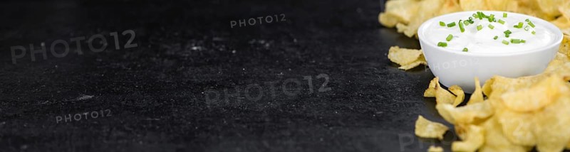 Some Potato Chips with Sour Cream taste on a slate slab (close-up shot, selective focus)
