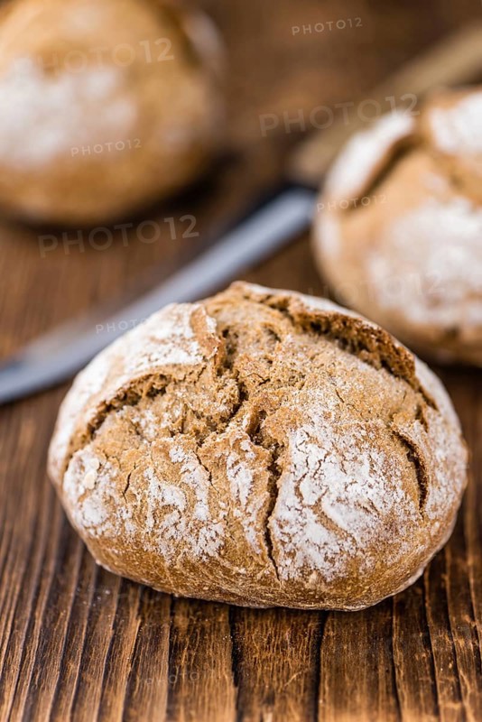 Wholemeal Roll on rustic wooden background (close-up shot)