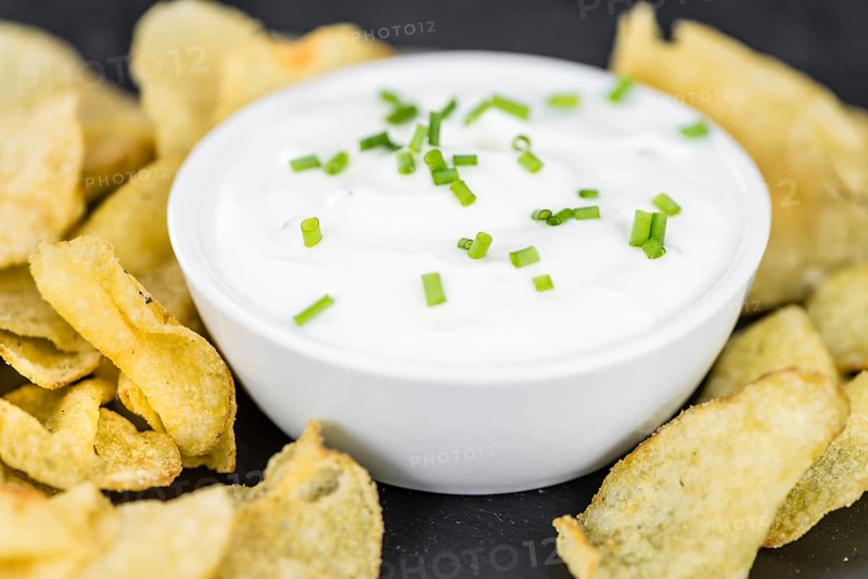 Fresh made Potato Chips with Sour Cream taste on a vintage background (close-up shot)