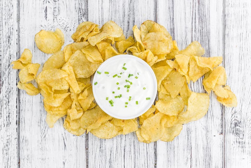 Potato Chips (Sour Cream taste) on a vintage background as detailed close-up shot (selective focus)