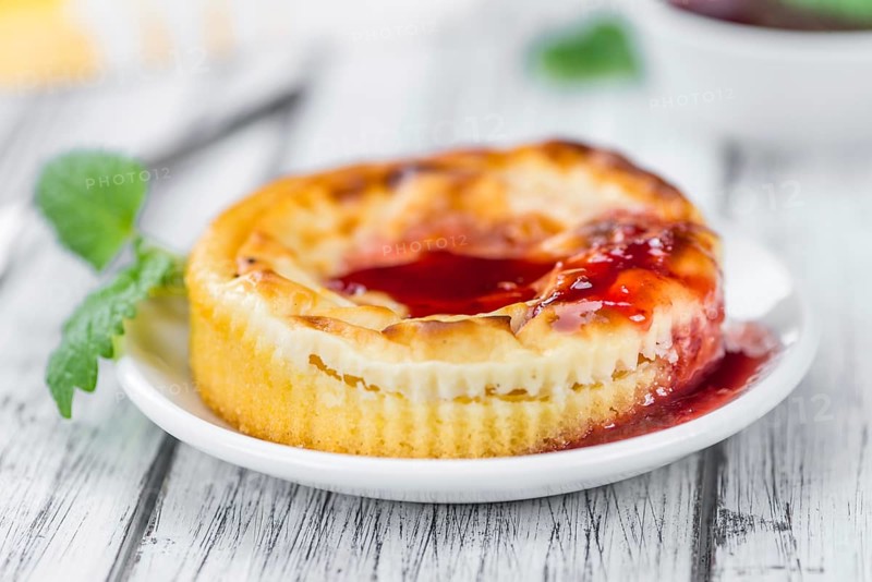 Mini Cheesecake (with Sauce) as high detailed close-up shot on a vintage wooden table (selective focus)