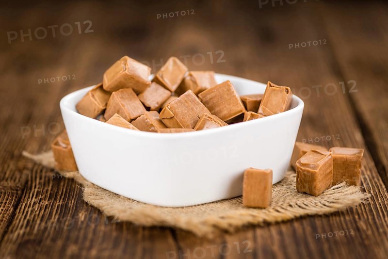 Caramel pieces as high detailed close-up shot on a vintage wooden table (selective focus)