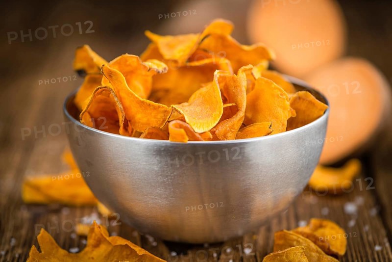 Sweet Potato Chips as high detailed close-up shot on a vintage wooden table, selective focus