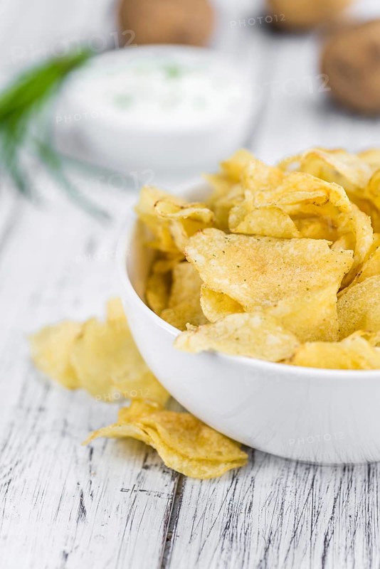 Potato Chips (Sour Cream taste) on a vintage background as detailed close-up shot (selective focus)