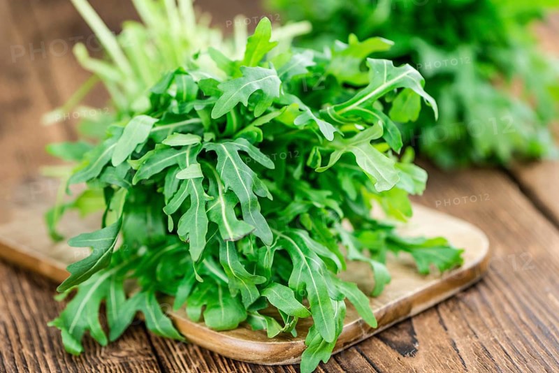 Fresh Arugula on an old wooden table as detailed close-up shot