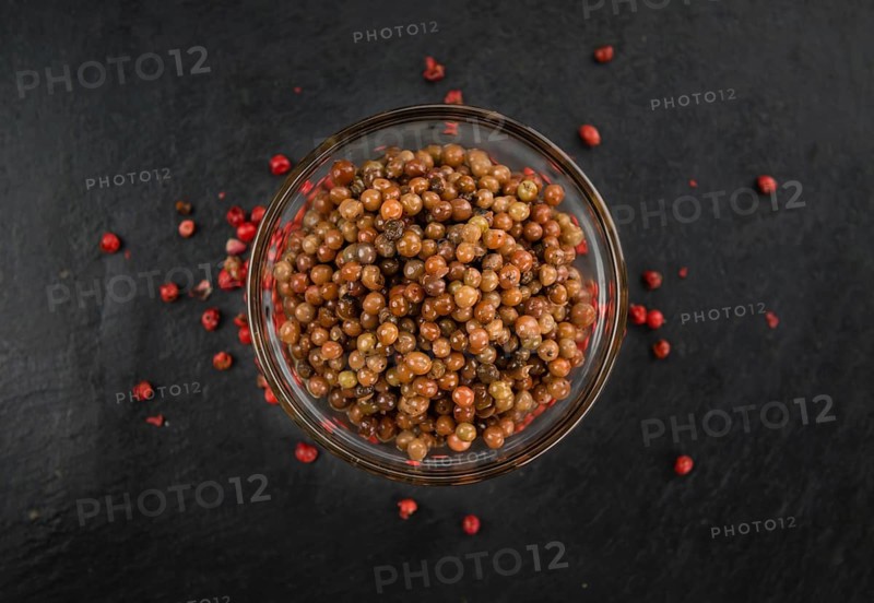 Some Pink Peppercorns (preserved) on a slate slab as detailed close-up shot, selective focus