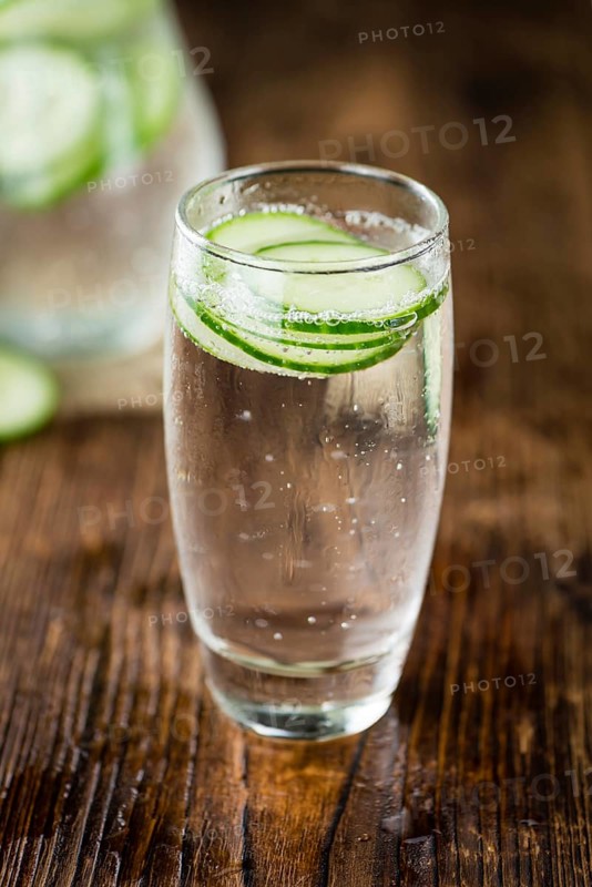 Fresh made Cucumber Water as high detailed close-up shot on a vintage wooden table, selective focus