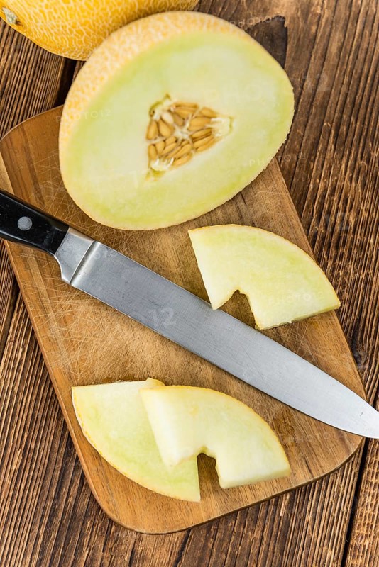 Honeydew Melon on an old wooden table as detailed close-up shot (selective focus)