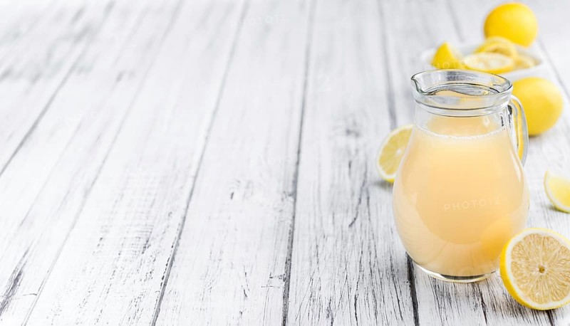 Fresh made Juice (lemon) on an old and rustic wooden table (selective focus, close-up shot)