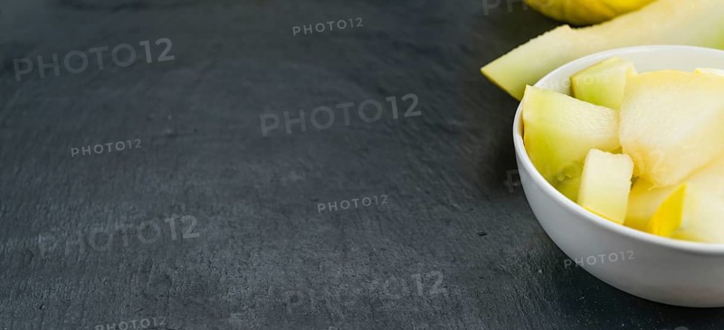 Portion of Honeydew Melon as detailed close up shot on a slate slab (selective focus)