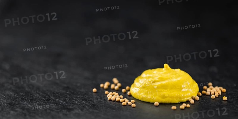 Fresh made Mustard on a vintage background (close-up shot)