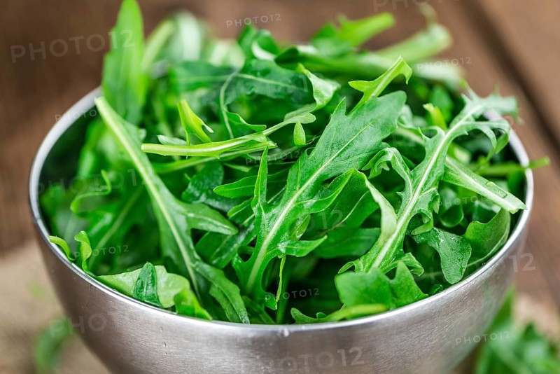 Fresh Arugula on an old wooden table as detailed close-up shot