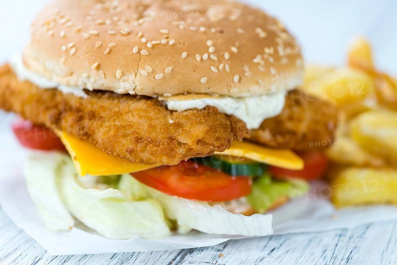 Wooden table with a fresh made Fish Burger (close-up shot, selective focus)