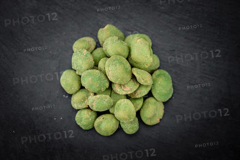 Portion of Wasabi coated Peanuts on a rustic slate slab (selective focus, close-up shot)